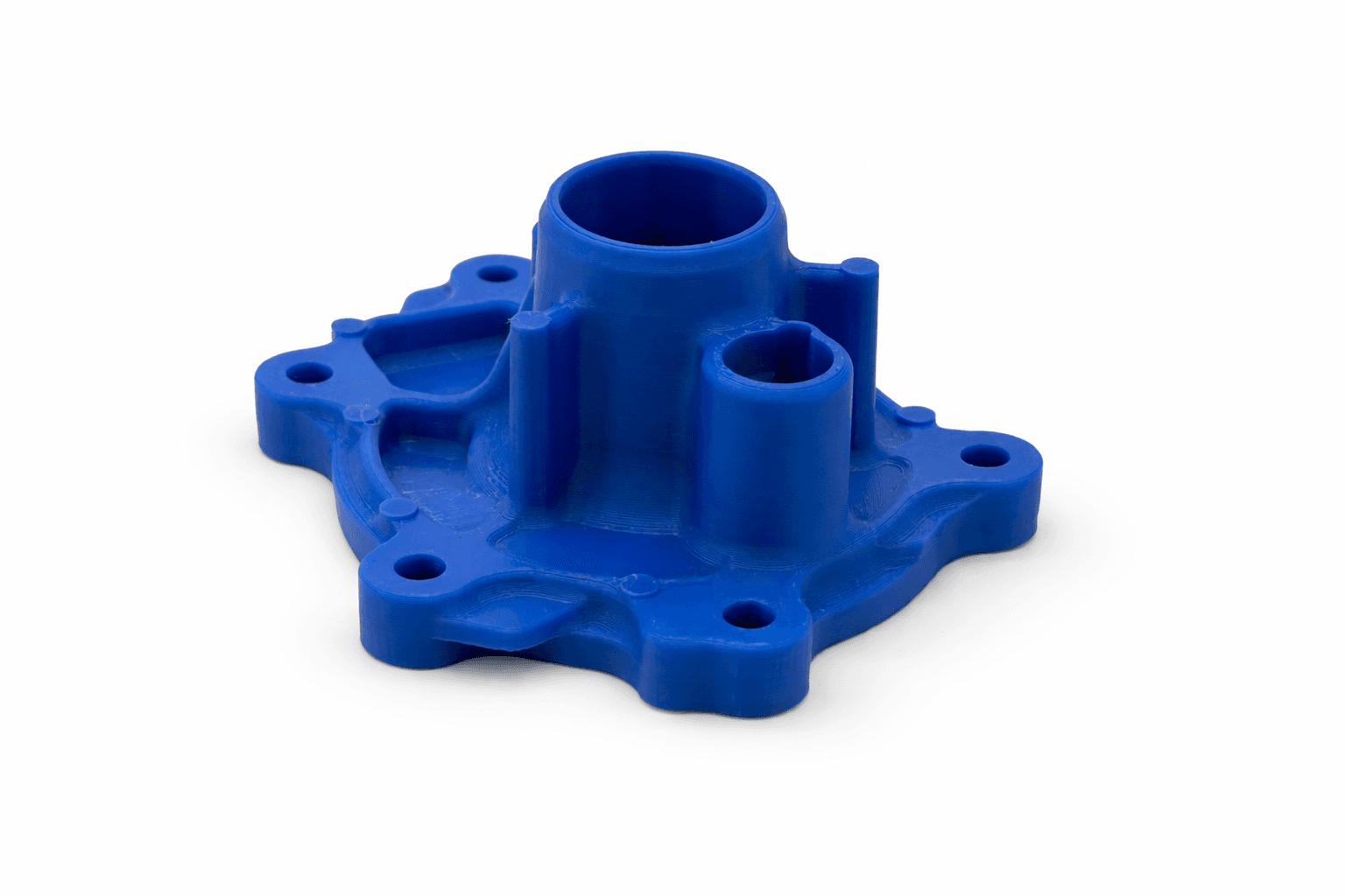 Blue 3D printed water-pump housing with a flanged bolt-down base and two cylindrical outlet ports — a legacy industrial equipment part reproduced at TAKT 3D