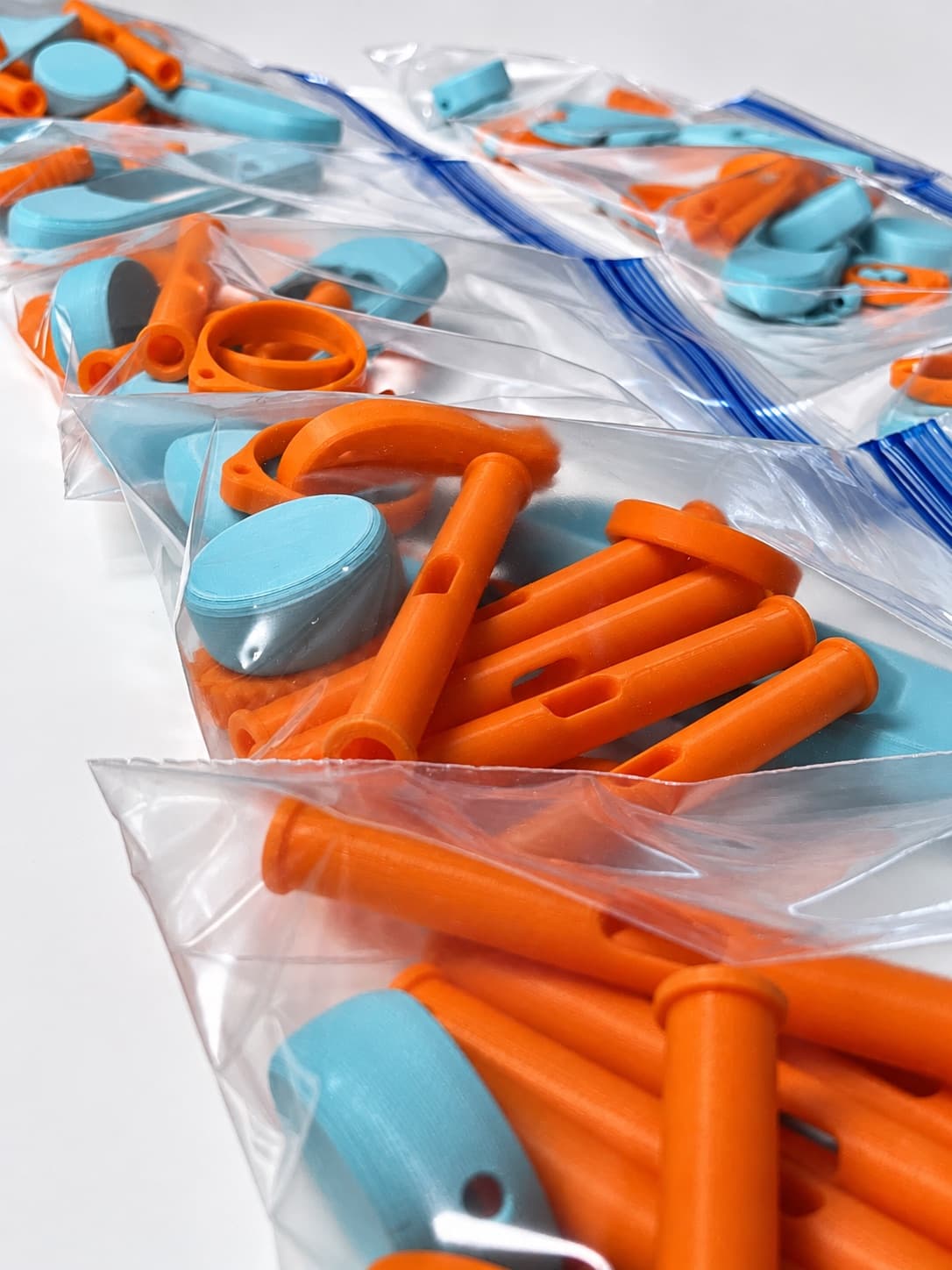 Orange and blue 3D printed parts bagged into production kits, ready to ship