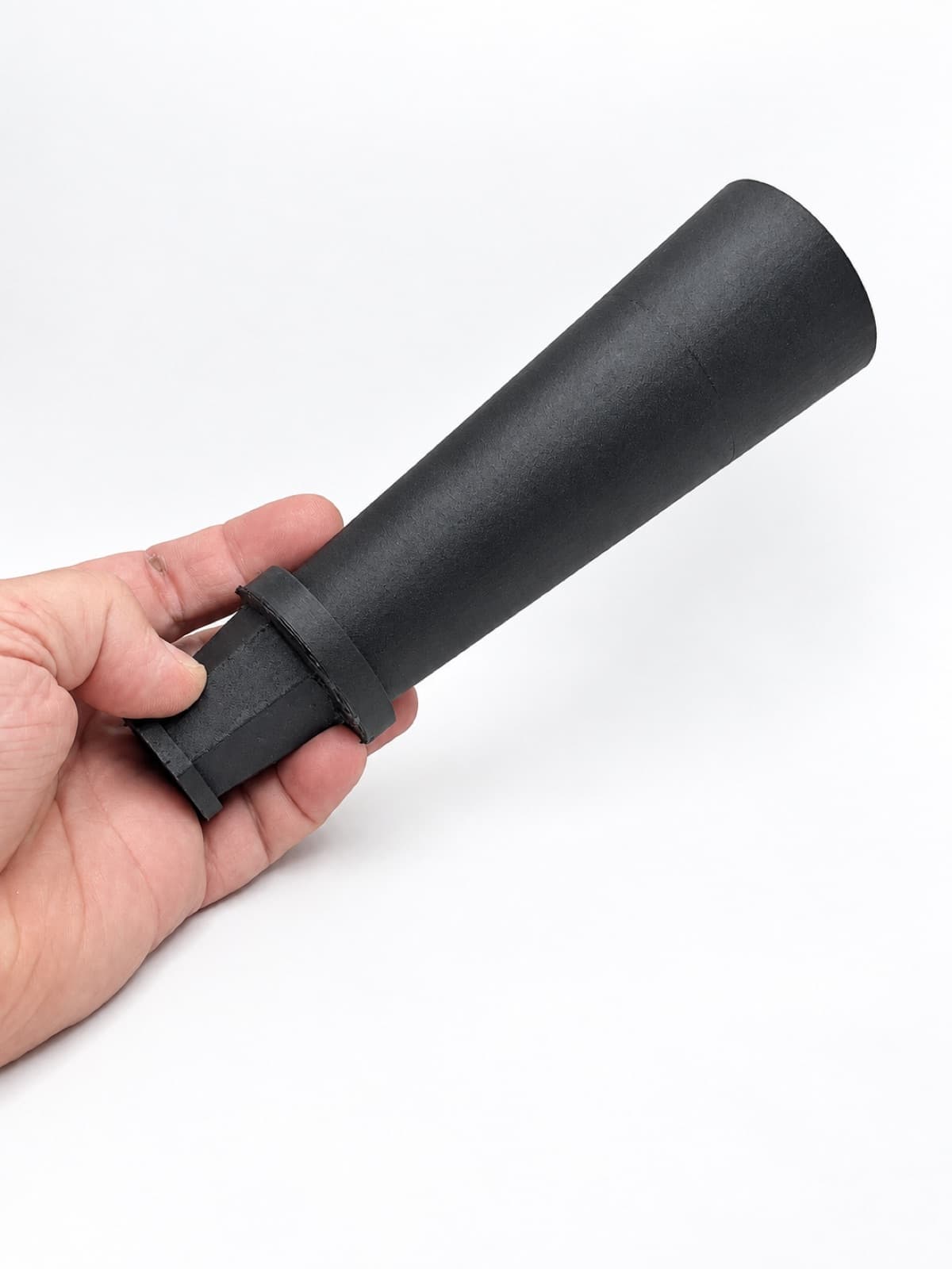 A hand holding a matte black 3D printed tapered horn with a flanged base