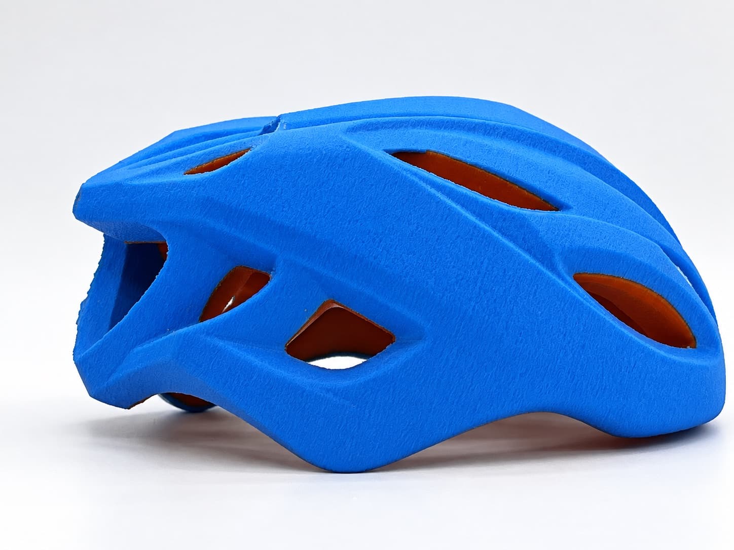 Blue two-color 3D printed bicycle helmet prototype with orange vent liner, printed for fit and form review