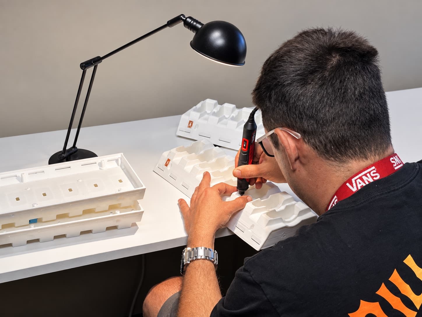 TAKT 3D technician hand-finishing a batch of white printed parts at the workbench