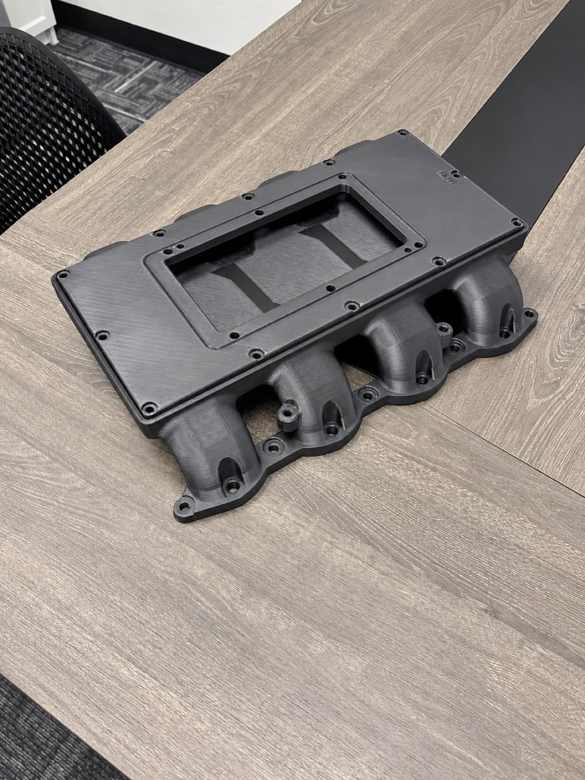 A large 3D printed manifold prototype, printed in sections and assembled, on the table at TAKT 3D in San Diego
