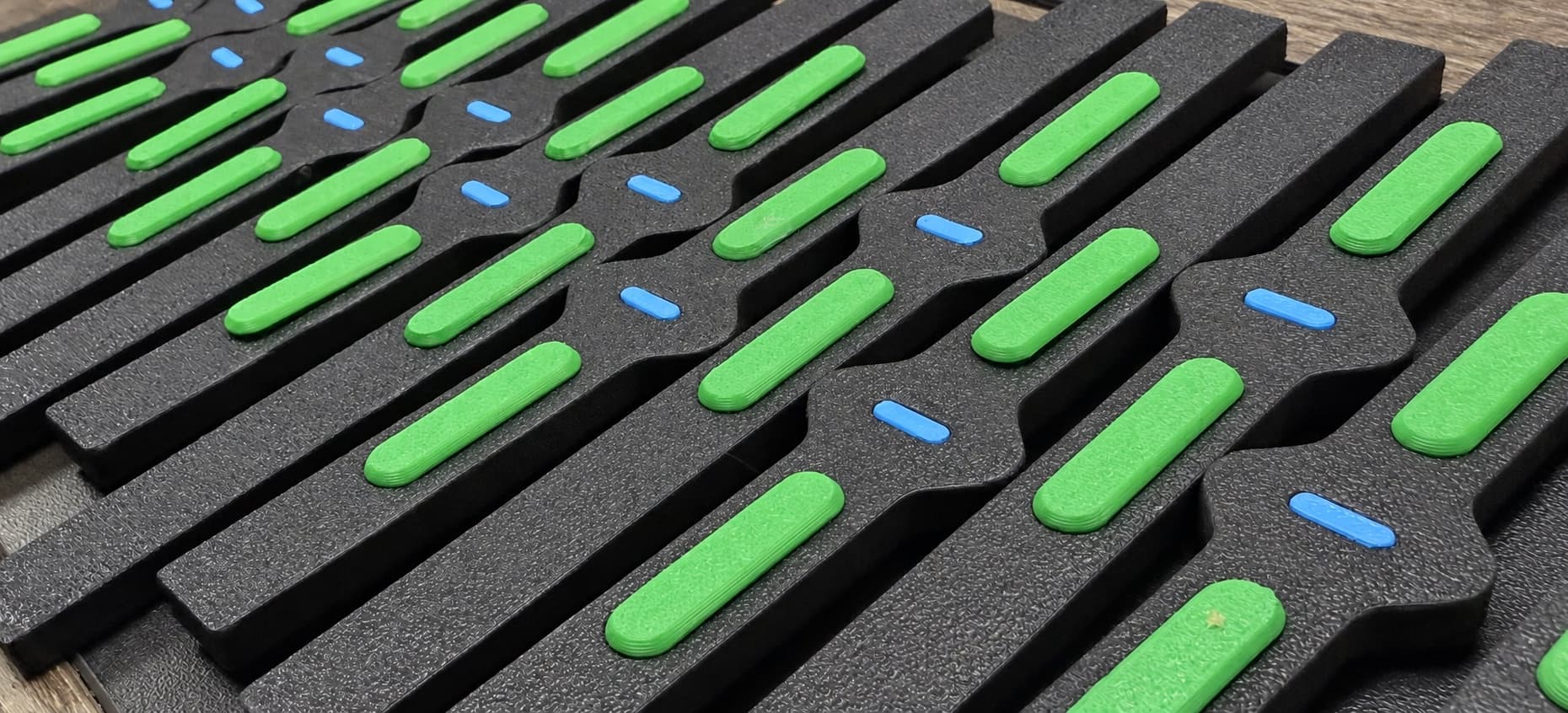 Black 3D printed rails with green and blue inserts, a production batch from the TAKT 3D shop in San Diego