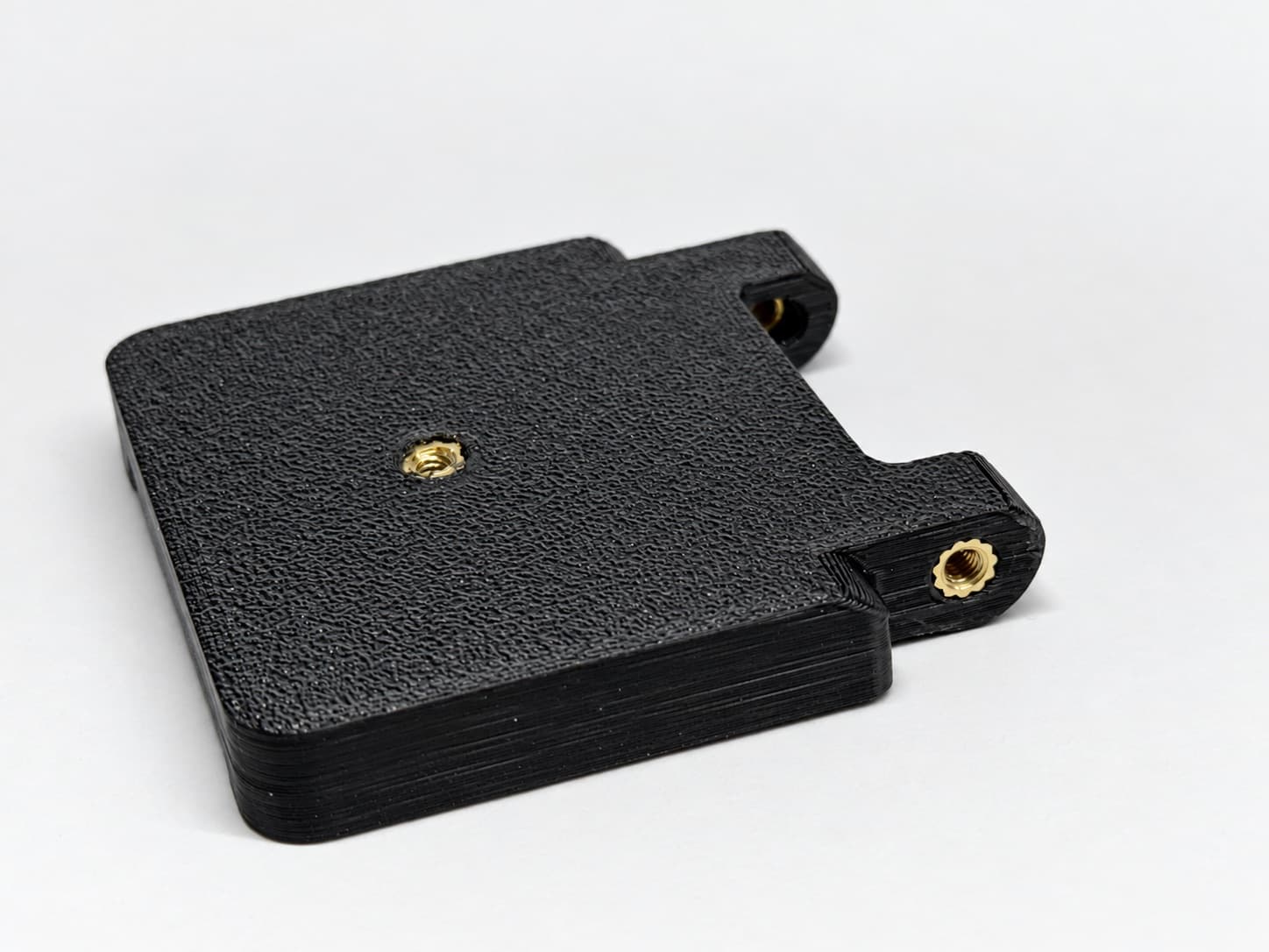 Black 3D printed mounting plate with heat-set brass threaded inserts installed — a finishing service performed in-house at TAKT 3D