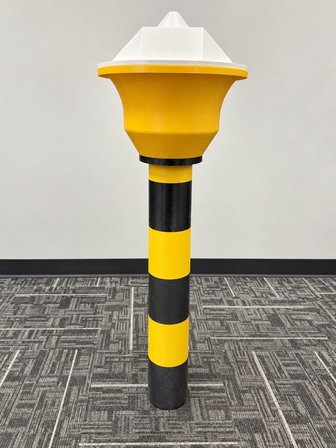 Yellow and black 3D printed safety bollard standing on the shop floor at TAKT 3D, printed on the large-format FDM line